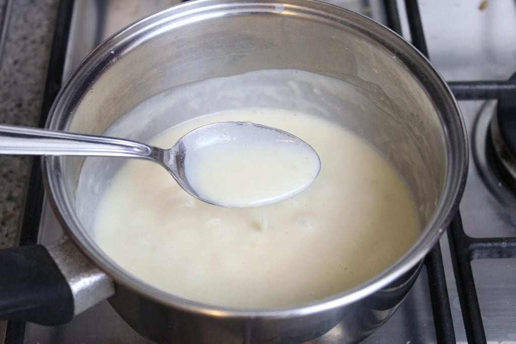 Nel frattempo, preparate la crema al latte. In un pentolino a fiamma spenta unite la panna, il latte, lo zucchero di canna, la vaniglia e 1 cucchiaio di farina setacciata. Accendete il fuoco e, mescolando in continuazione, lasciate cuocere fino a quando la crema non si sarà addensata. Ci vorranno circa 15 minuti.