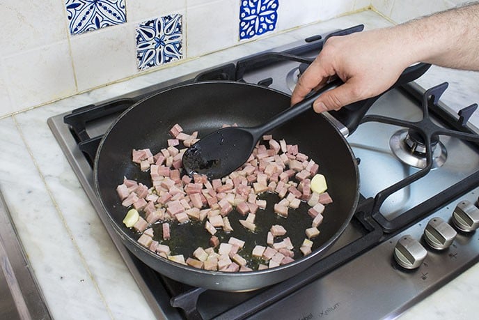 In una padella capiente, soffriggete uno spicchio d'aglio con un filo d'olio di oliva. Imbiondito l'aglio, aggiungete il prosciutto cotto a dadini e fatelo saltare in padella per un paio di minuti.   