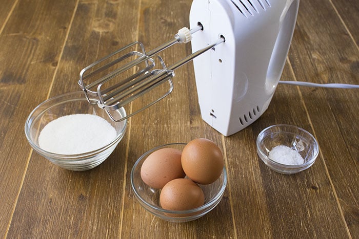 Con un classico cucchiaio da minestra, prendete 12 cucchiai di farina, 12 di acqua, 12 di zucchero e 12 di olio, in maniera tale da avere gli ingredienti già pronti al momento del loro utilizzo. In una ciotola capiente, lavorate con lo sbattitore elettrico le uova con lo zucchero e il pizzico di sale. Lavorate le uova per 3 - 4 minuti fino ad ottenere un composto chiaro e spumoso. 