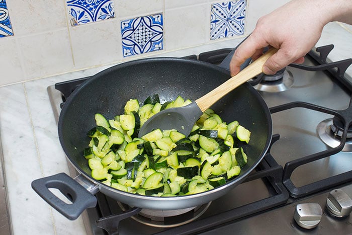 Tagliate le zucchine a cubetti e trasferitele in una padella capiente. Aggiungete uno spicchio d'aglio, mezzo bicchiere d'acqua, un filo d'olio d'oliva e infine salate e pepate secondo i vostri gusti. Accendete il fuoco e cuocete le zucchine per 10 minuti, mescolando di tanto in tanto. 