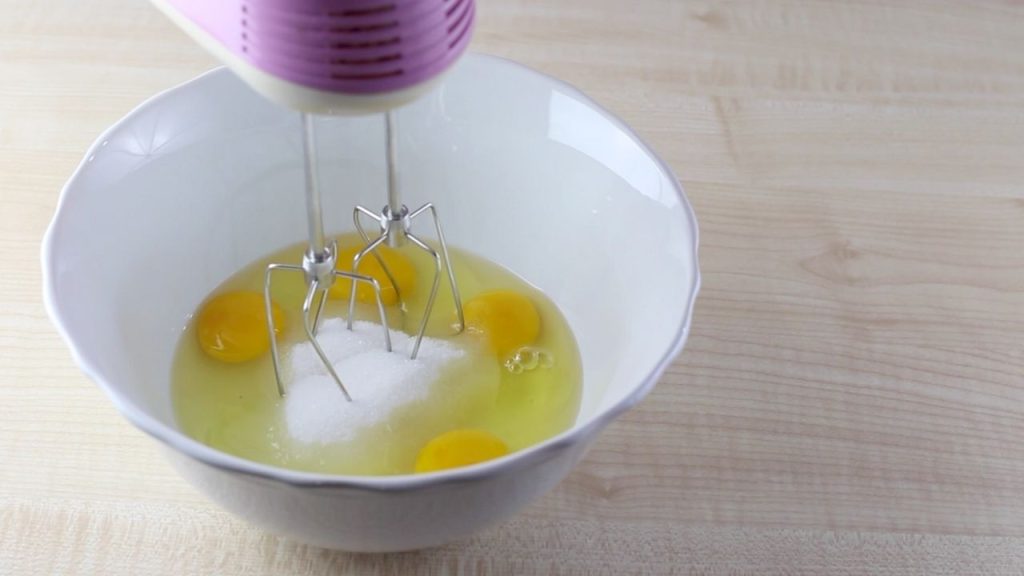 In una ciotola rompiamo le uova, aggiungiamo lo zucchero e iniziamo a mescolare con le fruste elettriche.