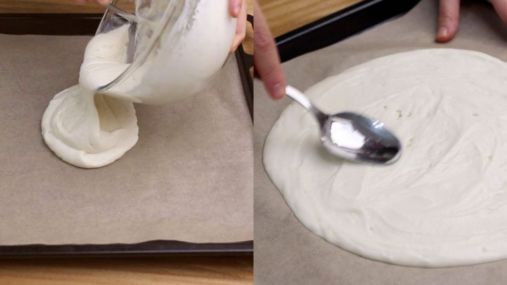 Mettiamo un foglio di carta forno sulla teglia da forno e versiamo la pastella al centro. Stendiamo l'impasto con un cucchiaio creando la classica forma rotonda della pizza. Lo spessore possiamo sceglierlo a seconda dei nostri gusti, calcolando che crescerà un pochino in cottura.