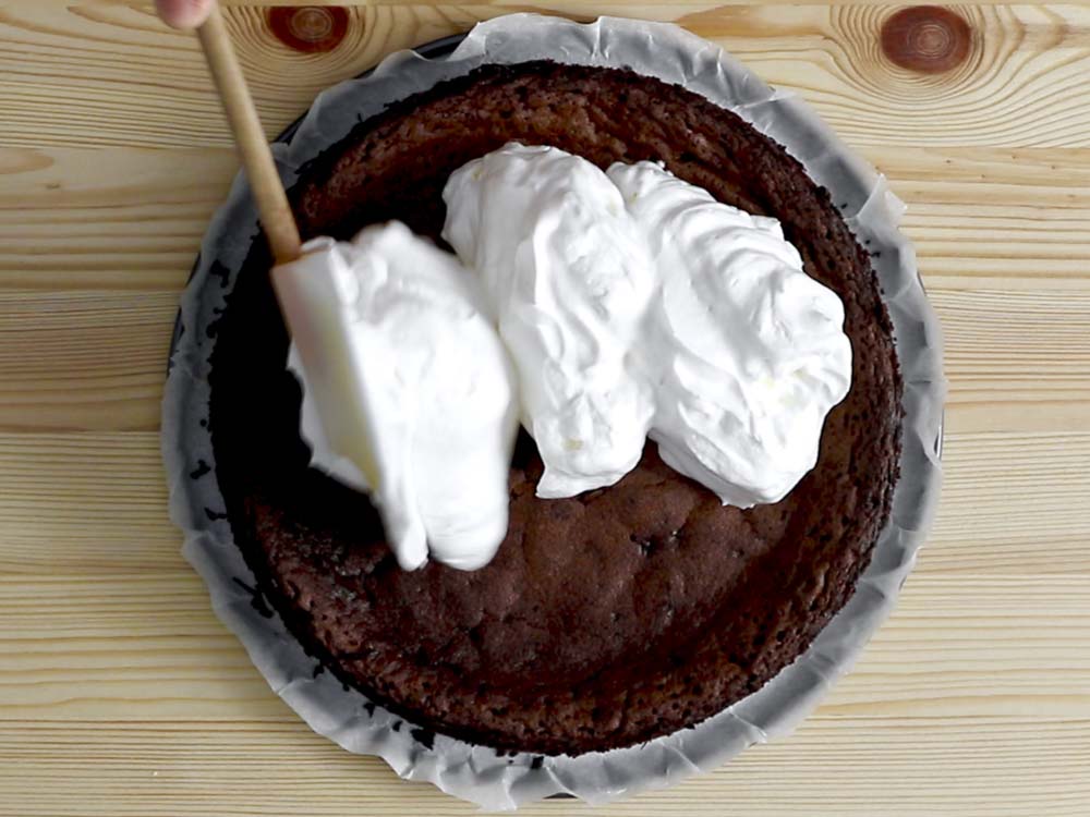Appena sfornata la torta, in una ciotola montiamo la panna zuccherata e la disponiamo sulla superficie della torta a formare tante morbide “nuvolette”.