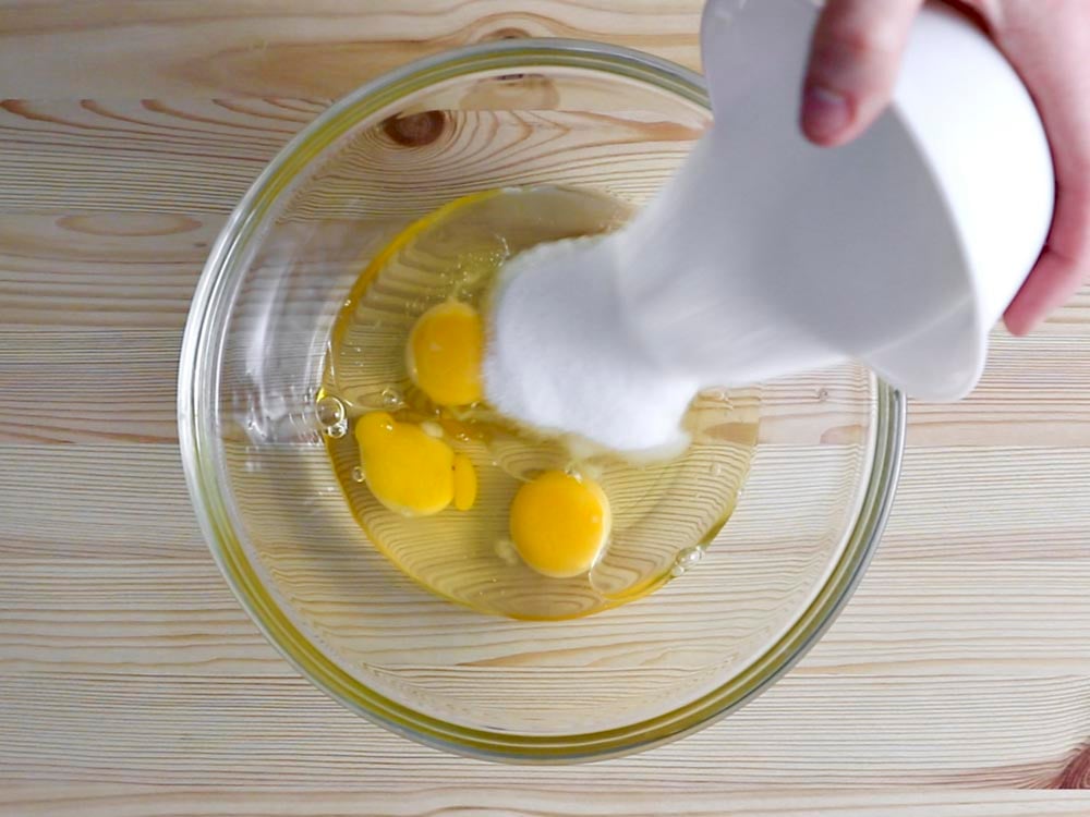 In una ciotola rompiamo le uova, aggiungiamo l’olio di semi di girasole, lo zucchero e mescoliamo tutto.