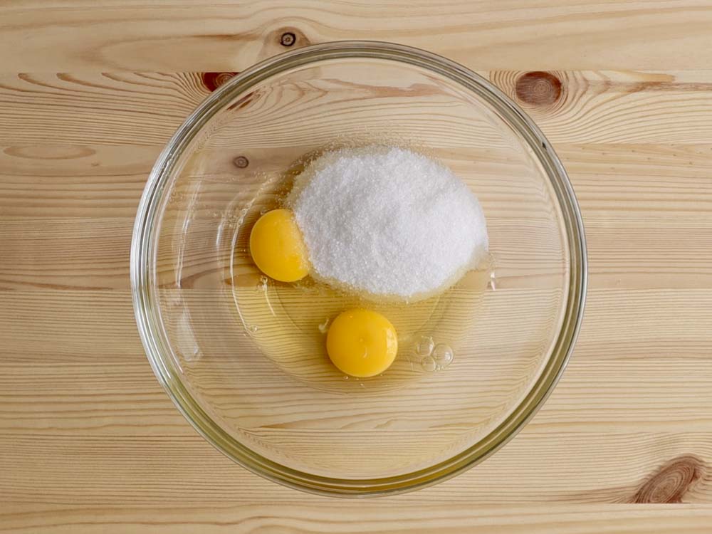 In una ciotola rompiamo le uova e mescoliamo con lo zucchero usando un cucchiaio.