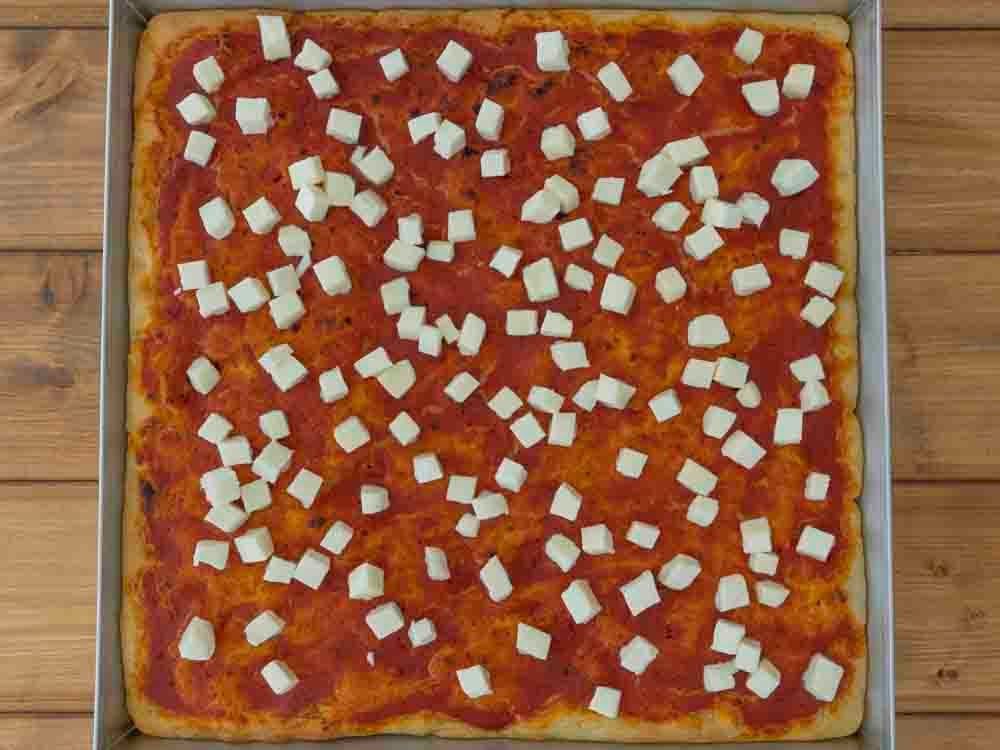Trascorso il tempo, sforniamo la pizza e aggiungiamo la mozzarella a dadini. Quindi mettiamo in forno per altri 5 minuti. 