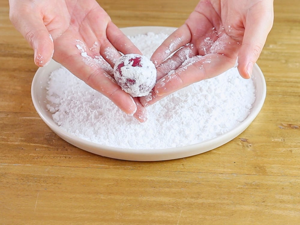 Passiamo le palline di impasto nello zucchero a velo.