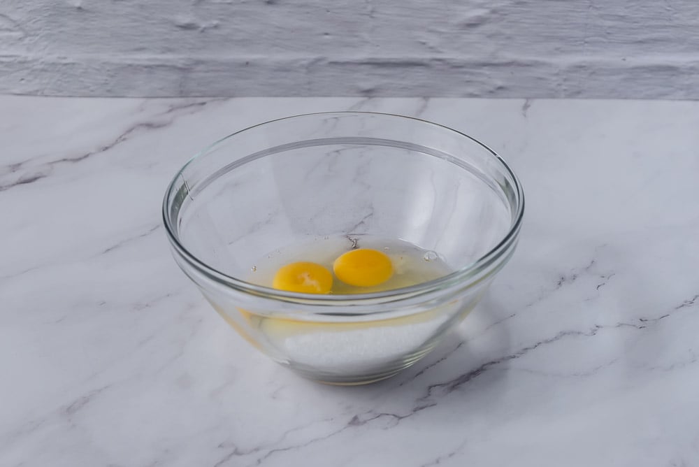 Mettiamo in una ciotola le uova e lo zucchero e mescoliamo con una frusta fino ad avere un composto chiaro e spumoso.