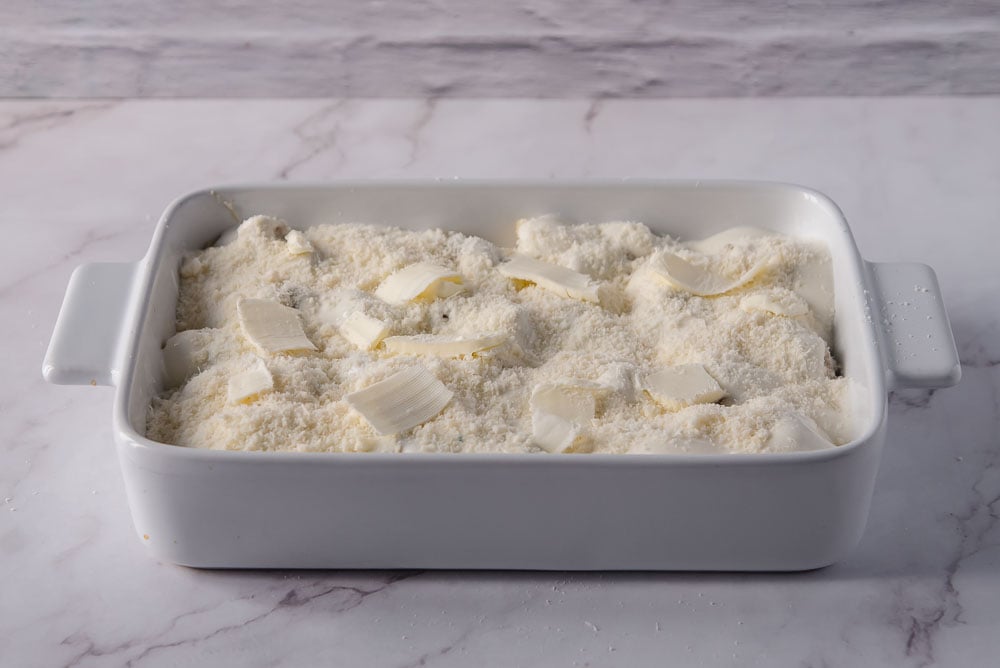 Mettiamo la besciamella rimasta sulla pasta e stendiamola delicatamente con un cucchiaio. Aggiungiamo poi il formaggio grattugiato rimasto e qualche fiocchetto di burro.